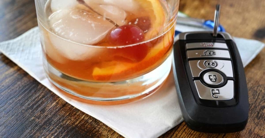 A glass of whiskey near a car key