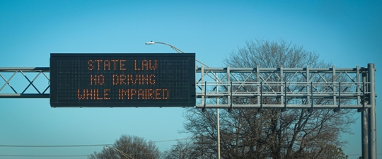 Road sign that says "State Law No Driving While Impaired"