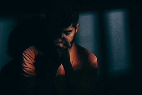 Prisoner man in dark cell depressed.